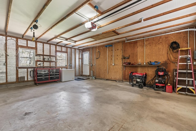 garage with a garage door opener, a workshop area, and wood walls