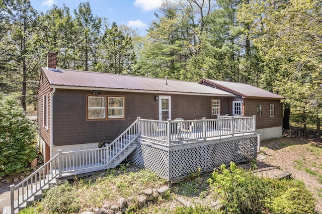 rear view of house with stairway, a wooden deck, metal roof, and a chimney