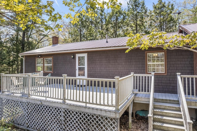 back of house featuring a chimney, a deck, and metal roof