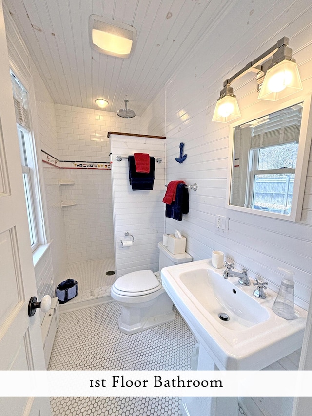 full bath featuring tiled shower, toilet, and a sink