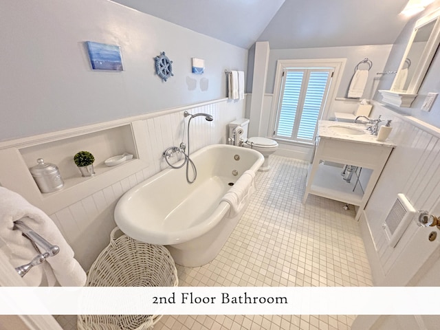 full bathroom with lofted ceiling, a bath, toilet, vanity, and tile patterned flooring