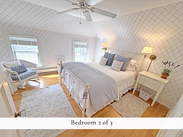 bedroom featuring light wood-style flooring, wallpapered walls, a baseboard heating unit, and ceiling fan