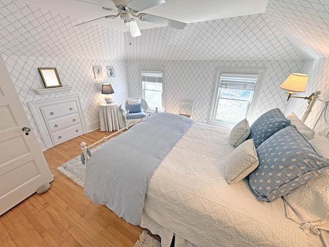 bedroom with wood finished floors, ceiling fan, and wallpapered walls