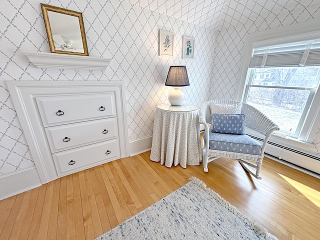 sitting room featuring light wood-style flooring, wallpapered walls, and baseboards