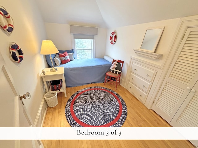 bedroom featuring light wood-style floors, baseboards, and lofted ceiling