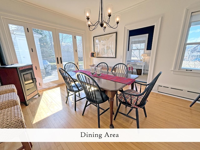 dining room with light wood finished floors, plenty of natural light, a chandelier, and ornamental molding