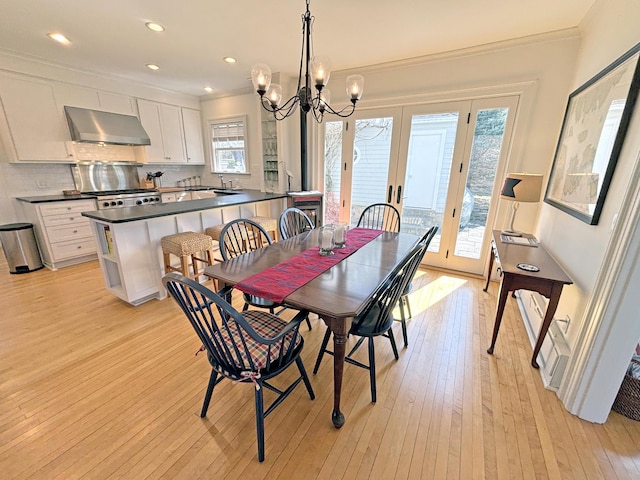 dining area with light wood-style floors, a chandelier, healthy amount of natural light, french doors, and crown molding