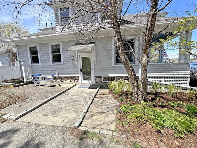 view of front of property featuring a patio area, a shingled roof, and fence