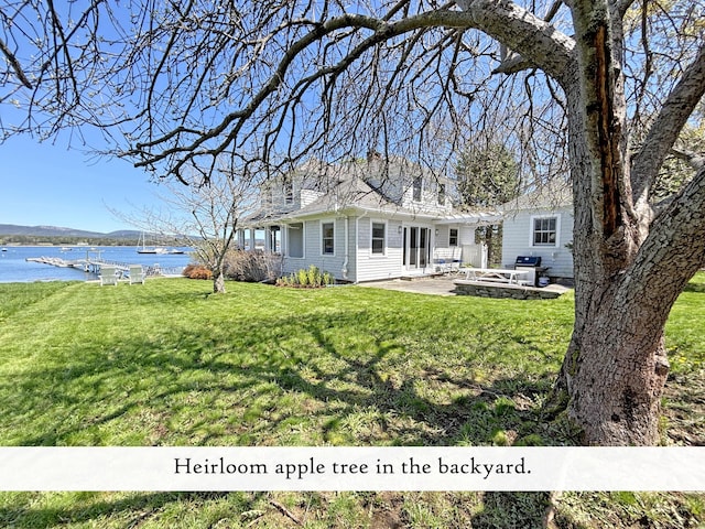 back of property featuring a water view, a patio, and a yard