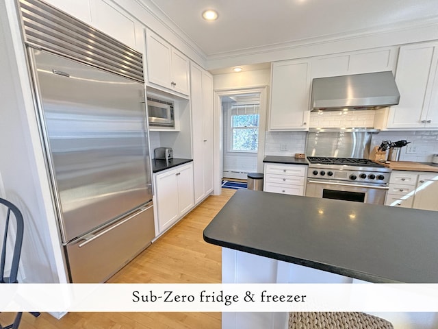 kitchen featuring built in appliances, ventilation hood, white cabinetry, crown molding, and recessed lighting