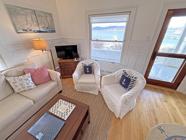 living room with a decorative wall, light wood-style flooring, healthy amount of natural light, and a wainscoted wall