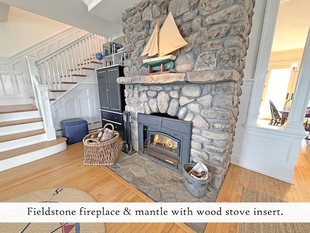 living area featuring hardwood / wood-style floors, a decorative wall, stairs, a baseboard heating unit, and a fireplace