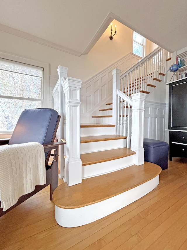 stairs featuring wood-type flooring, plenty of natural light, and a decorative wall