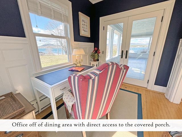 dining area with french doors, a decorative wall, wood finished floors, a wainscoted wall, and healthy amount of natural light