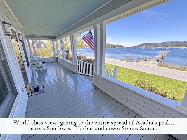 wooden deck with a porch, a water and mountain view, and a yard