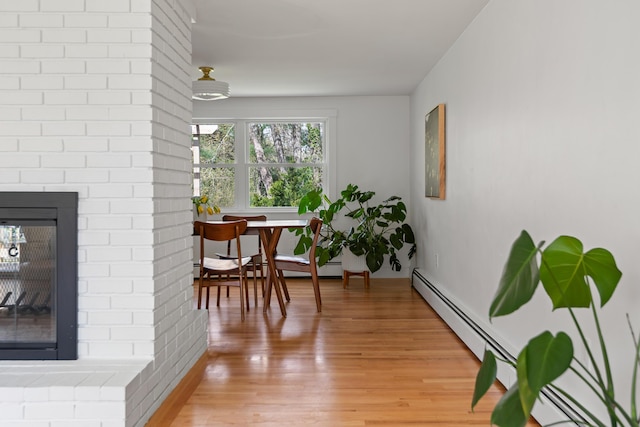 56 Carroll St, Falmouth, ME 04105 - dining space featuring light wood-type flooring, baseboards, a brick fireplace, and a baseboard heating unit