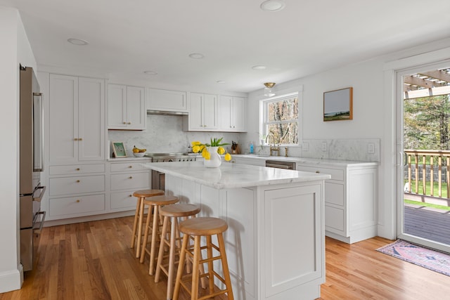 56 Carroll St, Falmouth, ME 04105 - kitchen featuring light wood finished floors, a kitchen bar, white cabinetry, a kitchen island, and recessed lighting