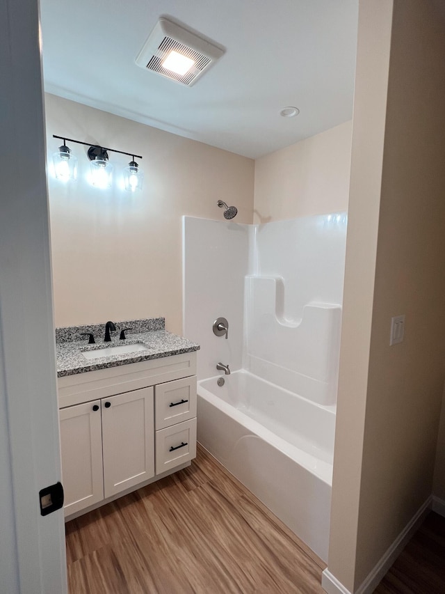 bathroom featuring wood finished floors, vanity, and tub / shower combination
