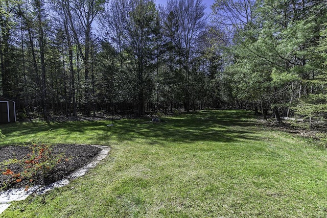 29 Fields Pond Rd, Holden, ME 04429 - view of green lawn with a storage shed, an outdoor structure, and a wooded view