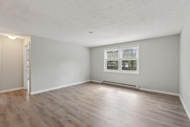 spare room featuring baseboard heating, a textured ceiling, wood finished floors, and baseboards