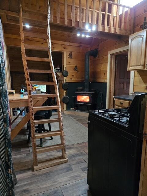 103 Fellows Ln, Winthrop, ME 04364 - kitchen featuring wooden walls, gas range oven, wood finished floors, a wood stove, and light brown cabinetry