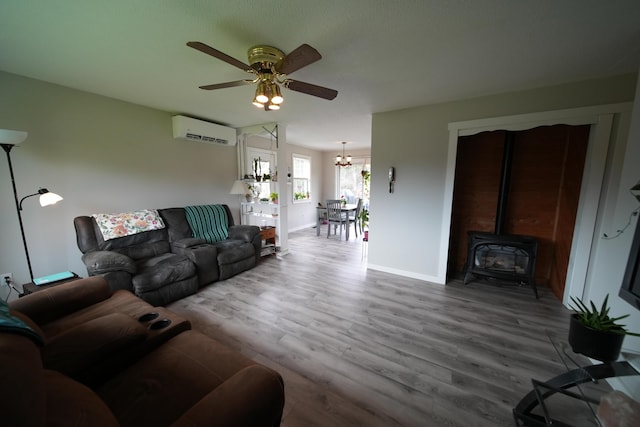 176 Smyrna Center Rd, Smyrna, ME 04780 - living area with a wall unit AC, a wood stove, a chandelier, ceiling fan, and wood finished floors