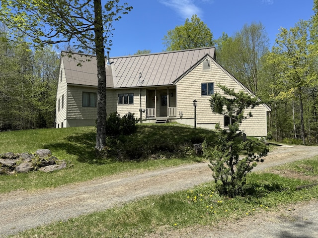 898 Sebec Village Rd, Sebec, ME 04481 - view of front facade featuring covered porch, dirt driveway, metal roof, and a standing seam roof