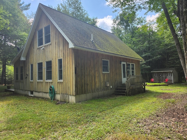 227 Brooks Pond Dr, Corinna, ME 04928 - view of side of property featuring a shed, a lawn, an outbuilding, a deck, and roof with shingles