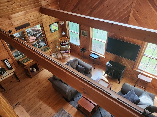 227 Brooks Pond Dr, Corinna, ME 04928 - living room with wood finished floors, wooden walls, healthy amount of natural light, lofted ceiling, and a wood stove