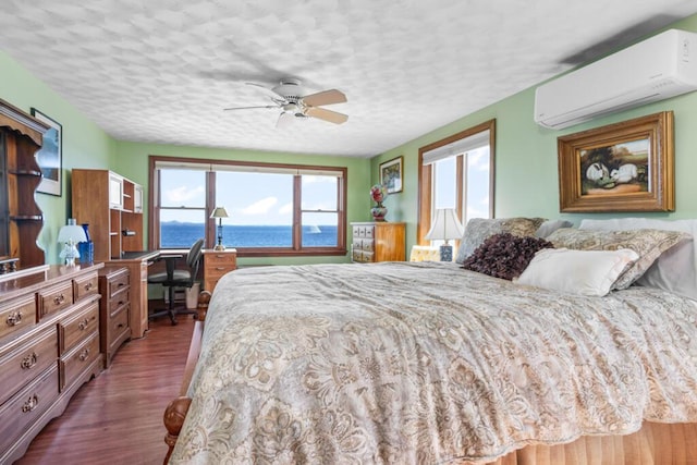 73 Wards Cove Rd, Standish, ME 04084 - bedroom featuring an AC wall unit, dark wood-type flooring, a water view, an office area, and a textured ceiling