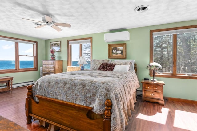 73 Wards Cove Rd, Standish, ME 04084 - bedroom featuring a wall unit AC, multiple windows, baseboards, wood finished floors, and a textured ceiling