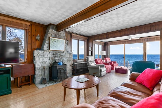 73 Wards Cove Rd, Standish, ME 04084 - living room featuring a water view, a wood stove, wood walls, light wood-type flooring, and a textured ceiling