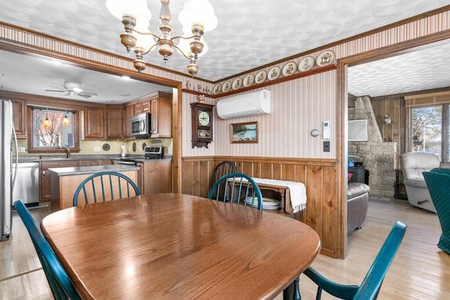 73 Wards Cove Rd, Standish, ME 04084 - dining space featuring a wall mounted AC, a chandelier, light wood-type flooring, a wainscoted wall, and a ceiling fan