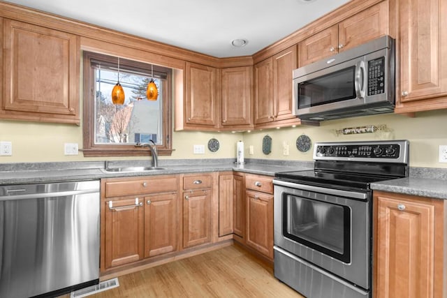 73 Wards Cove Rd, Standish, ME 04084 - kitchen featuring appliances with stainless steel finishes, a sink, light wood-style floors, and brown cabinetry