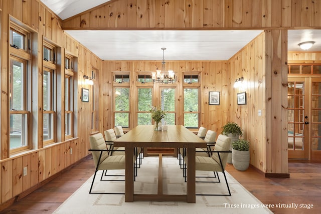 389 Castle Island Rd, Belgrade, ME 04917 - dining room featuring wooden walls, wood finished floors, a chandelier, lofted ceiling, and baseboards