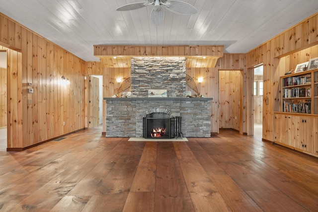 389 Castle Island Rd, Belgrade, ME 04917 - unfurnished living room with wooden walls, hardwood / wood-style flooring, a stone fireplace, ceiling fan, and wood ceiling