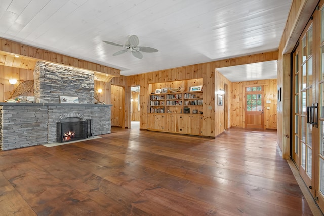389 Castle Island Rd, Belgrade, ME 04917 - unfurnished living room with wood walls, ceiling fan, hardwood / wood-style floors, a stone fireplace, and wooden ceiling