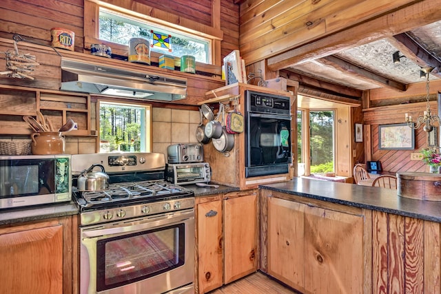 890 Salem Rd, Freeman Twp, ME 04983 - kitchen with appliances with stainless steel finishes, wood walls, exhaust hood, healthy amount of natural light, and dark countertops