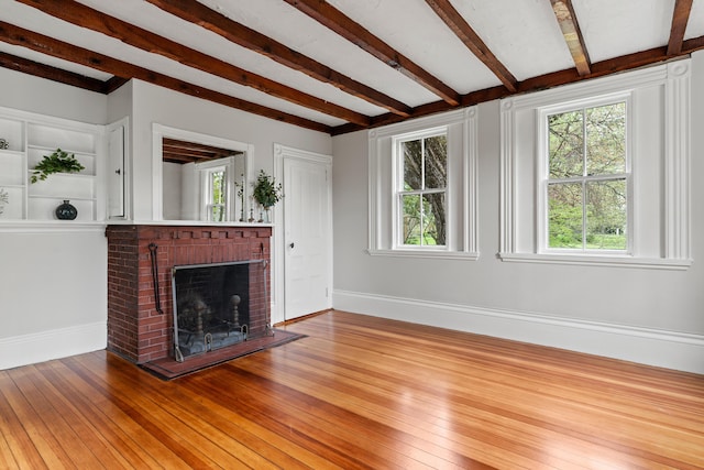 288 Foreside Rd, Falmouth, ME 04105 - unfurnished living room featuring a brick fireplace, plenty of natural light, hardwood / wood-style flooring, baseboards, and beamed ceiling