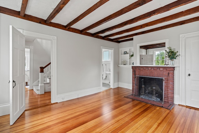 288 Foreside Rd, Falmouth, ME 04105 - unfurnished living room with stairs, hardwood / wood-style floors, beamed ceiling, plenty of natural light, and a brick fireplace
