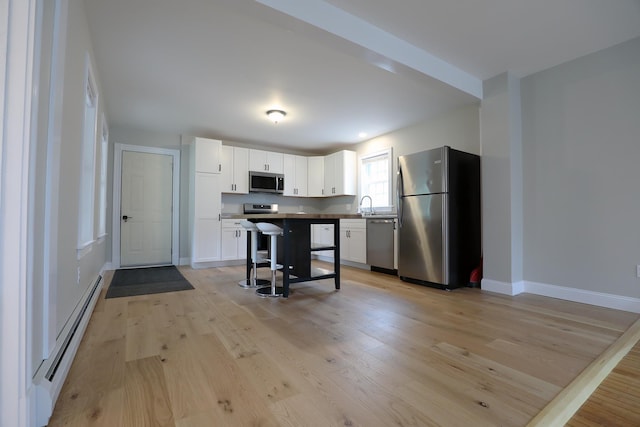 7 Middle St, Hallowell, ME 04347 - kitchen featuring appliances with stainless steel finishes, baseboard heating, white cabinetry, and light wood-type flooring