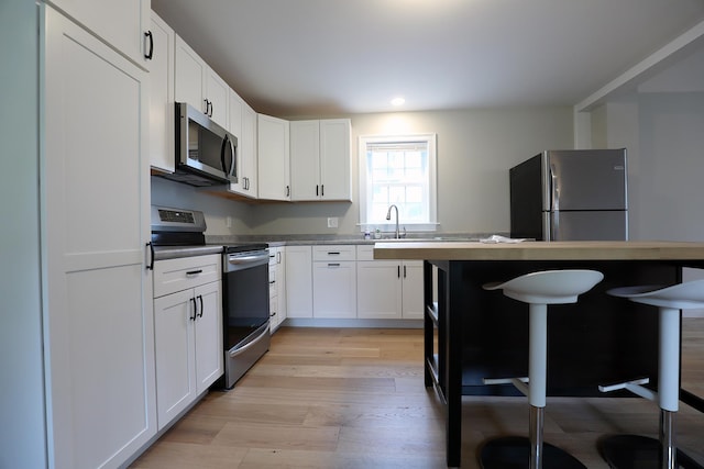 7 Middle St, Hallowell, ME 04347 - kitchen featuring appliances with stainless steel finishes, light wood-style flooring, white cabinetry, a kitchen bar, and recessed lighting