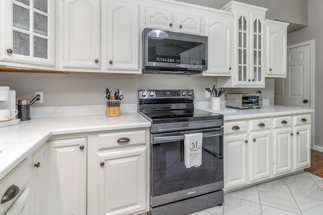 320 Grove St, Lewiston, ME 04240 - kitchen featuring stainless steel appliances, white cabinets, glass insert cabinets, and light countertops