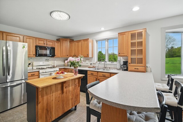 94 Staples Hill Rd, Canton, ME 04221 - kitchen featuring black appliances, a sink, a breakfast bar, decorative backsplash, and a peninsula