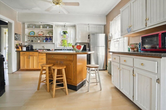 139 S Ave, Lewiston, ME 04240 - kitchen with freestanding refrigerator, a kitchen bar, a center island, ceiling fan, and light wood-type flooring