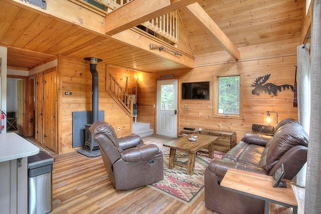 231 Kendall Farm Trl, Rangeley, ME 04970 - living area with wood ceiling, light wood finished floors, a wood stove, wooden walls, and stairs