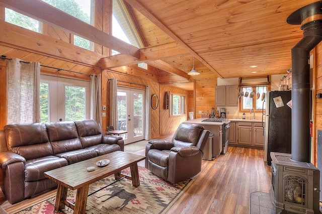 231 Kendall Farm Trl, Rangeley, ME 04970 - living area with a wood stove, wood walls, light wood-style flooring, wood ceiling, and beamed ceiling