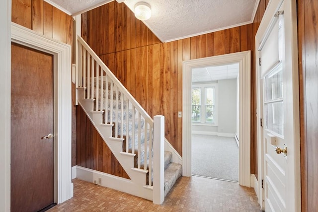 stairs featuring wooden walls and a textured ceiling