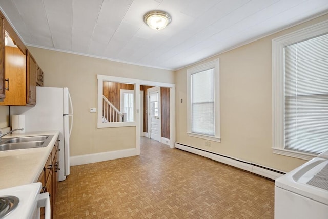 kitchen with brown cabinetry, washer / dryer, stove, a baseboard radiator, and light countertops