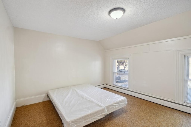 carpeted bedroom featuring baseboard heating, a textured ceiling, lofted ceiling, and baseboards